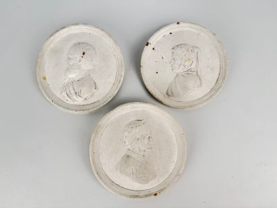 trois assiettes blanches sur lesquelles figurent les portraits d'un homme et d'une femme