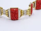 two gold and red bracelets on a white surface with a white background