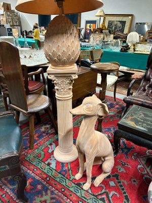 une statue représentant un chien assis à côté d'une lampe posée sur une table