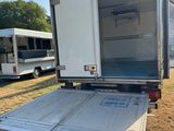 l'arrière d'un camion blanc dont la porte est ouverte, dans un champ