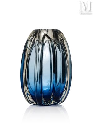 un vase en verre bleu avec un socle en argent, posé sur une surface blanche