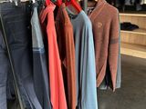 clothes hanging on a rack in a clothing store with a brick wall in the background
