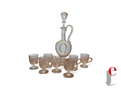 une carafe en argent et en verre ainsi que des tasses posées sur une table