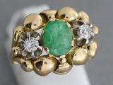gros plan d'une bague avec une pierre verte entourée de diamants