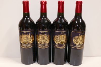 quatre bouteilles de vin rouge sont alignées sur une table