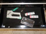 a stapler, glue gun, and toothpaste in a drawer