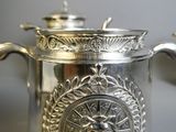 a silver coffee pot with a decorative design on it