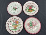 four plates decorated with flowers and leaves on a black surface