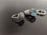 two rings with blue topaz and white topaz crystals on a black surface