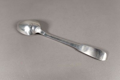 une cuillère en argent avec un manche de cuillère sur une surface grise