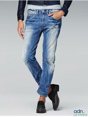 Cet homme porte une chemise noire et un jean bleu.