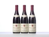 three bottles of red wine sit on a white surface