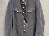 une vieille veste militaire accrochée au mur à côté d'un cintre en bois