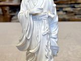 a white statue of a man holding a bowl on a table