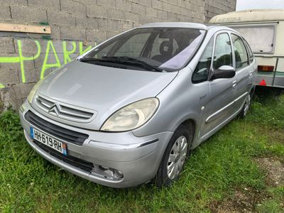 a silver car parked next to a trailer in the grass