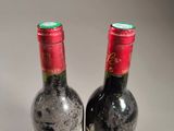 two bottles of red wine sitting next to each other on a table