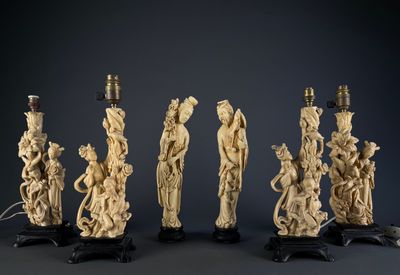 six carved ivory figurines with figures on stands on a table