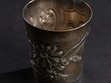 a silver cup sitting on a table with a black background
