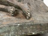 a bronze statue of a dog laying on a rock