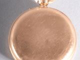 a gold pocket watch hanging from a string on a table