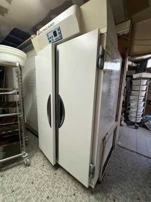 un grand réfrigérateur blanc dans une pièce où se trouve un étagère remplie de provisions