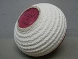 un bol blanc au crochet orné d'un bouton rouge