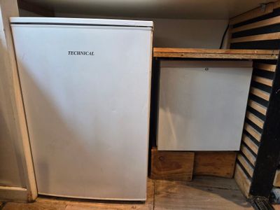 un petit réfrigérateur blanc dans le coin d'une pièce