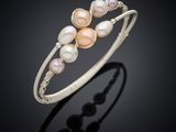 a close up of a bracelet with pearls on a black background