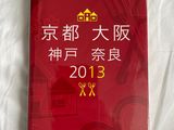 menu d'un restaurant chinois posé sur un lit aux draps blancs et à la couverture rouge