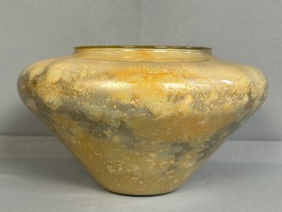 un grand vase jaune posé sur une surface blanche