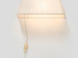 a white wall lamp with a white shade on the side of it