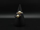 un gros plan d'une bague ornée de deux perles sur un cône noir