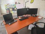 a desk with three computers and a chair in front of it