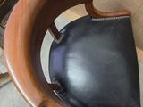 a wooden chair with a black leather cushion on it