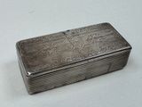 une boîte ancienne en argent posée sur une table blanche, sur fond blanc
