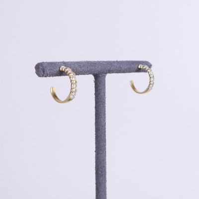 a pair of gold hoop earrings on a stand