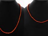 a pair of red coral necklaces on a mannequin