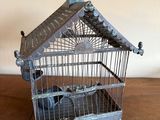 une cage à oiseaux avec un oiseau à l'intérieur, posée sur une table en bois