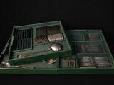 a green tray with silverware in it on a black background