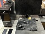 a desk with a computer, keyboard, mouse, and other items on it