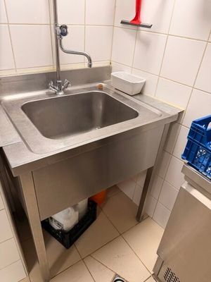a stainless steel sink in the corner of a bathroom
