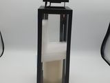 a black lantern with a candle inside of it on a white surface