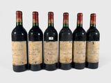 six bottles of wine are lined up in a row on a white surface