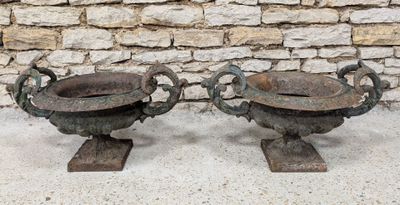 deux grands pots en métal posés près d'un mur de pierre