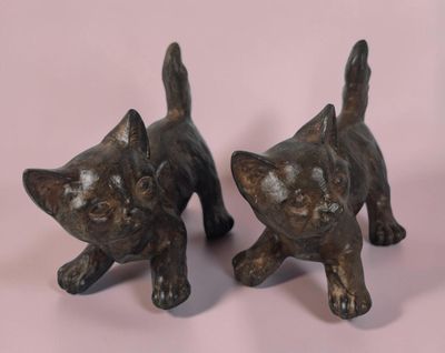 une paire de figurines de chats en bronze sur fond rose
