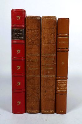 three old books are lined up in a row on a white surface