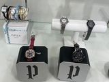 three watches on display in a glass case