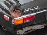 a black car with a rusted tail light on it ' s rear end