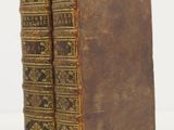 two old books sitting on top of each other on a white surface