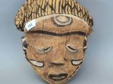 une image représentant un masque en bois sur fond gris